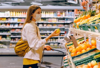 woman holding a basket doing grocery shopping whilst wearing covid-19 face mask