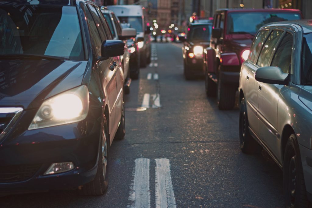 front shot of line of cars in two lanes with headlights on