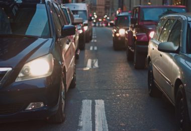 front shot of line of cars in two lanes with headlights on