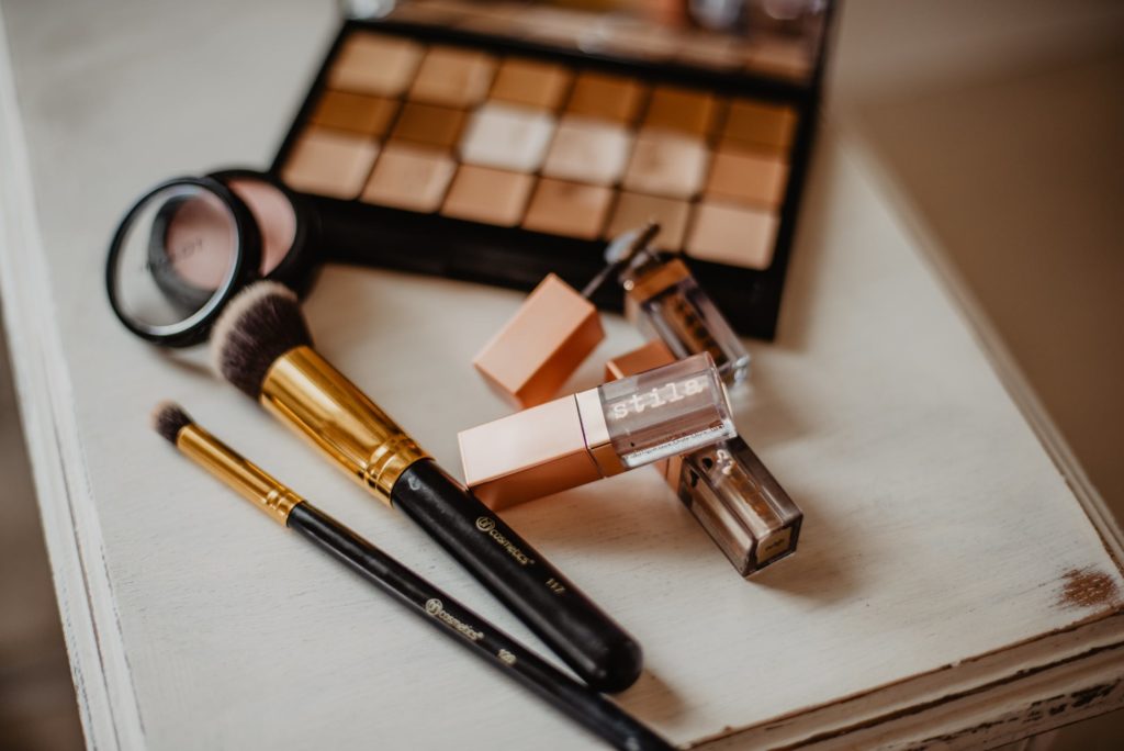 on a table, makeup brushes, lip glosses, blush and eyeshadow palette