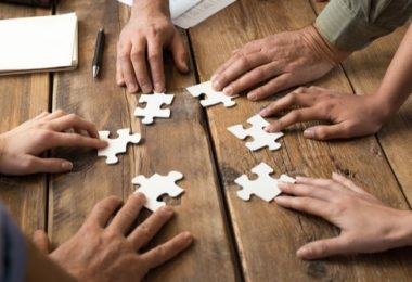 hands resting on jigsaw puzzle pieces on table