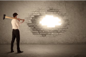 man with hammer looking at hole in broken brick wall