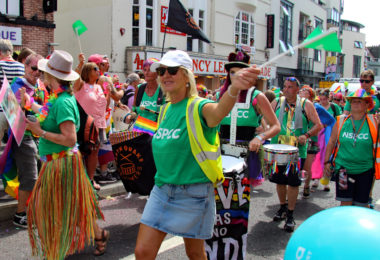 crowd of people wearing NSPCC branded tops whilst taking part in a carnival march