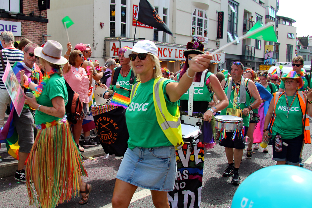 crowd of people wearing NSPCC branded tops whilst taking part in a carnival march